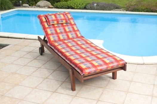 A wooden garden deckchair standing by the pool