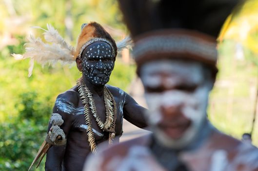 INDONESIA, IRIAN JAYA, ASMAT PROVINCE, JOW VILLAGE - JUNY 28:   The Headhunter of a tribe of Asmat shows traditional and national dresses on June 28,INDONESIA, IRIAN JAYA, ASMAT PROVINCE, JOW VILLAGE - JUNY 28: The Portrait Asmat warrior with a traditional painting and coloring on a face. June 28, 2012 in Jow Village, Asmat province, Indonesia