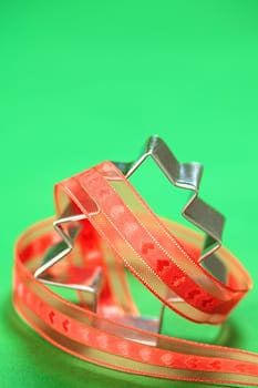 Christmas tree shaped cookie cutter with red ribbon on green (Selective Focus, Focus on the tip of the cookie cutter)