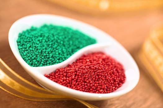 Red and green colored sugar sprinkles used for decorating Christmas cookies with golden ribbon around (Selective Focus, Focus one third into the red sprinkles)