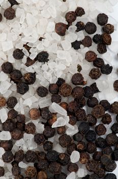 Background of Whole Black Peppercorns and Crystal Sea Salt closeup