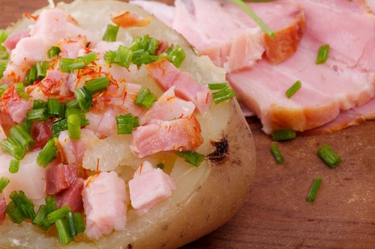 Baked Jacket Potato with Bacon, Paprika, Butter and Spring Onion closeup on wooden background