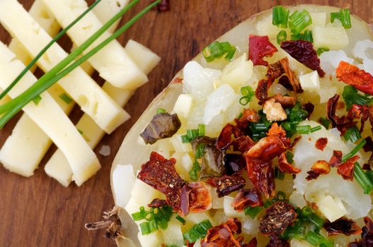 Baked Potato with Cheese, Paprika and Spring Onion closeup on Wooden plate 