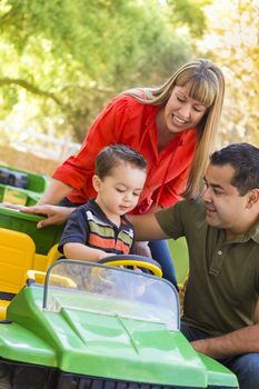 Happy Young Mixed Race Boy Enjoys A Toy Tractor While Parents Look On.