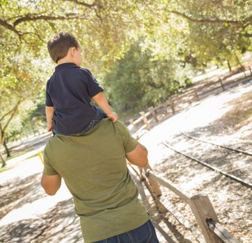 Happy Mixed Race Son Enjoys a Piggy Back Ride in the Park with Dad.