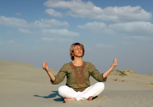 beautiful woman meditating in desert
