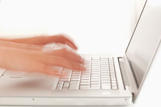 Slightly blurred hands heading to keyboard of laptop