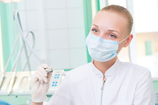 female dentists in protective mask holds a dental drill, the doctors at work