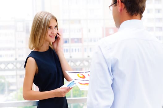 business male and business female discuss reports, Woman talking on cell phone