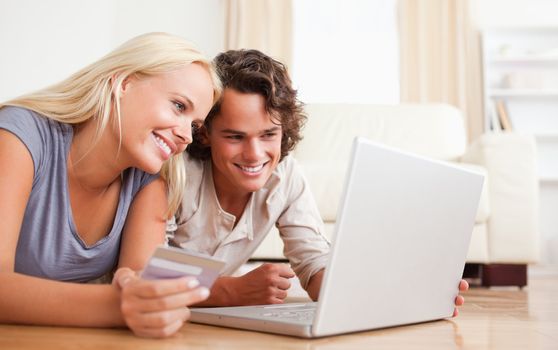Close up of couple purchasing online while lying on the floor
