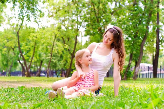 mother and daughter sitting together on the grass, and spend time with family