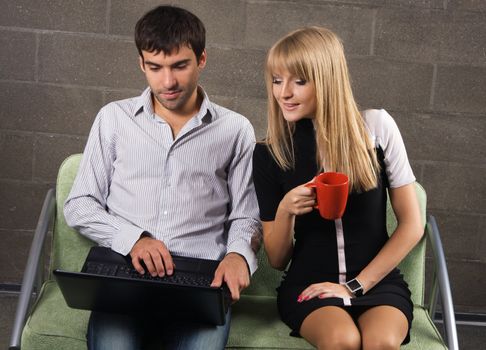 Young man and woman sitting with a laptop indoors