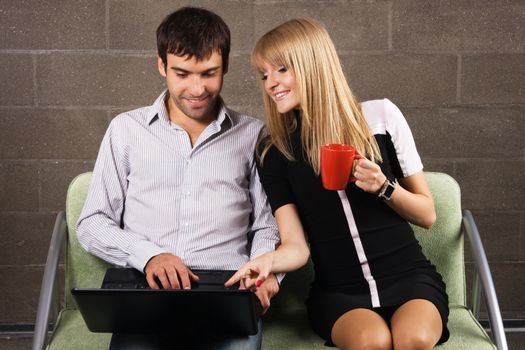 Young man and woman sitting with a laptop indoors 