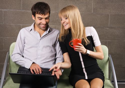 Young man and woman sitting with a laptop indoors