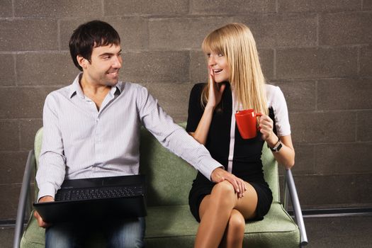 Young man and woman sitting with a laptop indoors