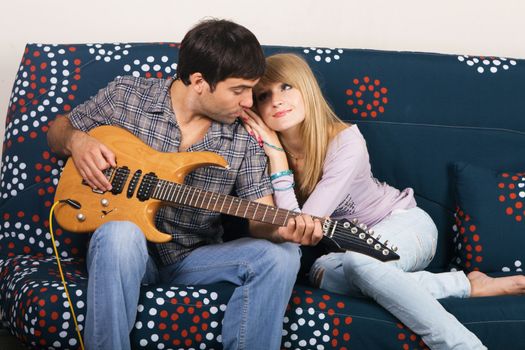 Romantic young couple resting on a sofa with a music
