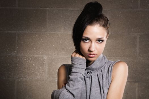 Beautiful model in gray dress on brick wall background