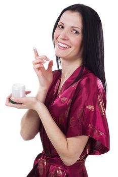 Lovely woman applying moisturizing cream on her face, white background
