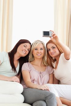 Young women lounging on a sofa with a camera in a living room