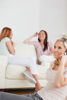 Joyful woman with a phone separated from the others in a living room