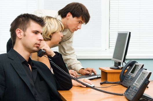 Young businessman making a phone call, with his team working in the background