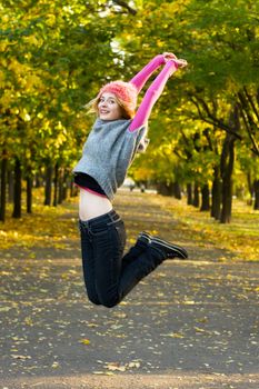 Joyful young woman jumping in autumn park