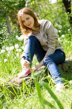 Portrait of a beautiful young woman sitting in dandelions