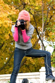 Cute girl taking a photograph in an autumn park
