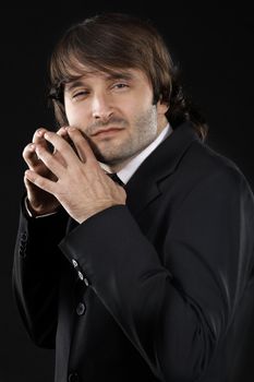 Sly man in elegant suit against black background