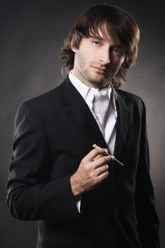 Portrait of an elegant handsome man with cigar over black background