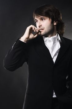 Portrait of an elegant handsome man with cigar over black background 
