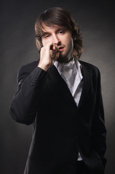 Portrait of an elegant handsome man against with cigar black background