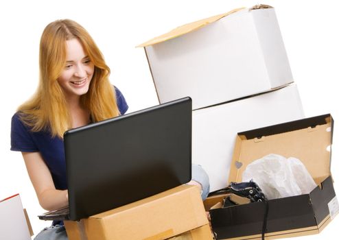 Young beautisul woman surrounded by delivered orders, surfing an online store at her laptop