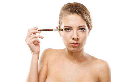 Portrait of a beautiful young woman applying makeup