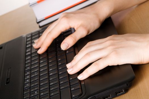 Hands of a woman working at her laptop, closeup photo