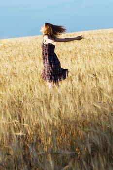 Beautfiul woman in checkered dress in a wheat field