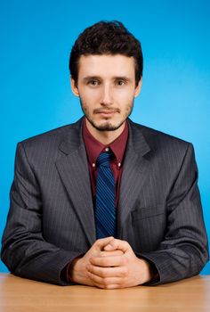 Young handsome businessman studio portrait, blue background