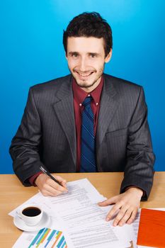 Young handsome businessman working with documents, blue background