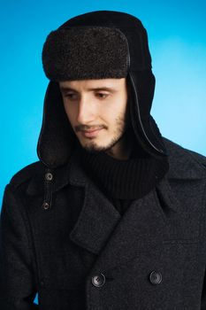 Handsome young man in winter clothing, blue background