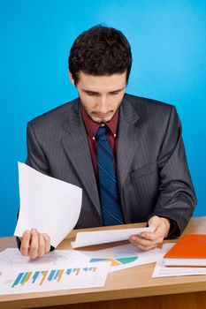 Young handsome businessman working with documents, blue background