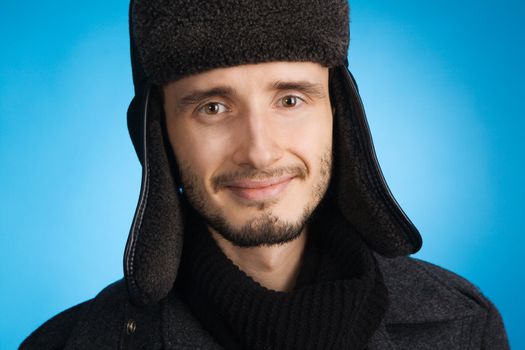 Handsome young man in winter clothing, blue background