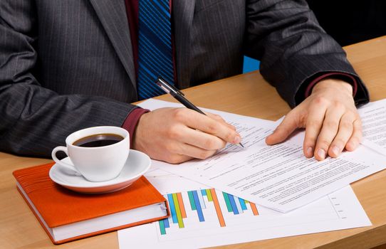 Businessman working at table covered with documents