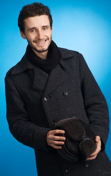 Handsome young man in winter clothing, blue background