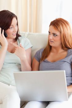 Upset Women sitting on a sofa with a laptop and a phone in a living room