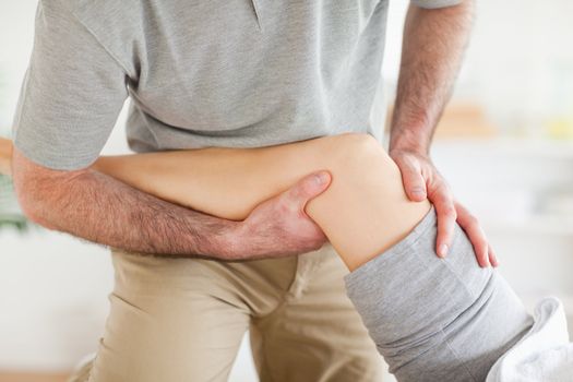 Chiropractor massaging a woman's knee in a room