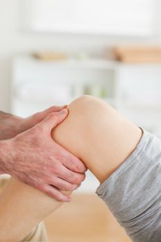 Guy massaging a lying woman's knee in a room