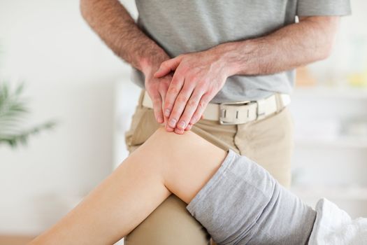 Chiropractor massaging a cute woman's knee in a room