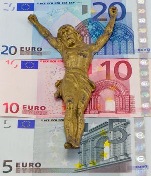 Gold jesus crucify on euro banknotes. Concept of europe finance crisis. Five ten and twenty euro banknotes.