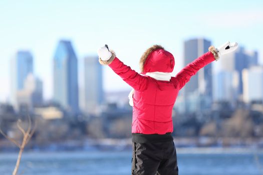 Happy winter woman in city excited and cheering with arms raised in happiness. Beautiful young woman and Montreal City skyline, Quebec, Canada.