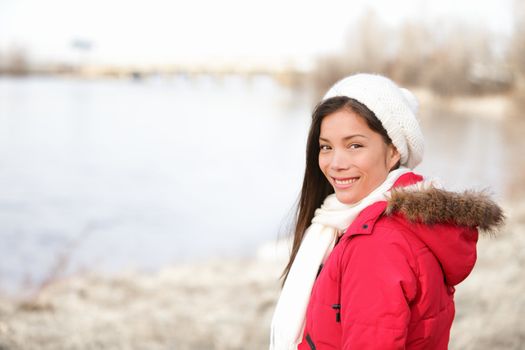 Winter woman portrait outside. Mixed-race girl smiling happy in cold winter landscape wearing warm winter clothing smiling happy looking at camera. Asian Chinese and Caucasian ethnicity. From Quebec, Canada.